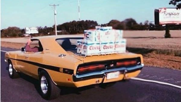 Yellow pickup truck with boxes on the back driving on a road.